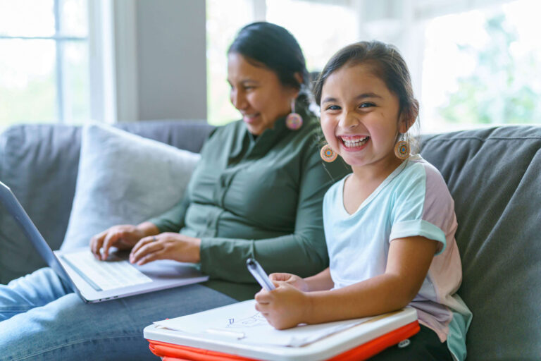 Woman and child sit on couch together smiling.