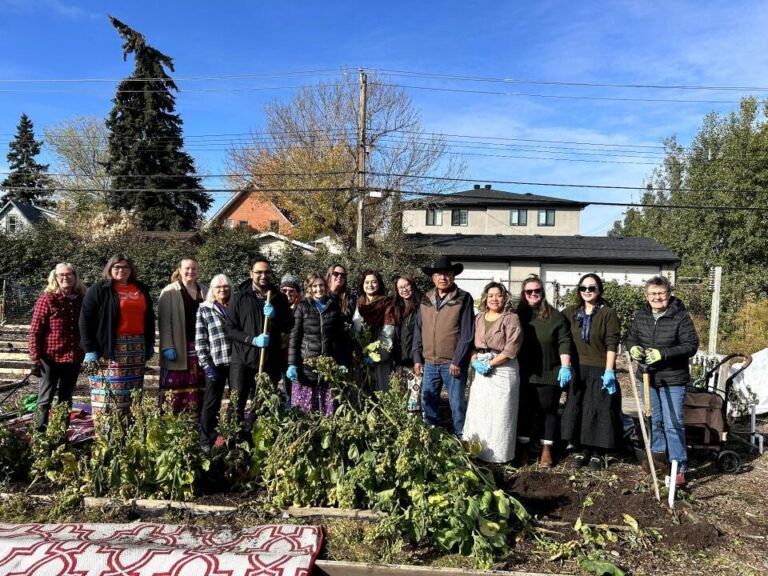 Group of people standing with harvested tobacco plants.